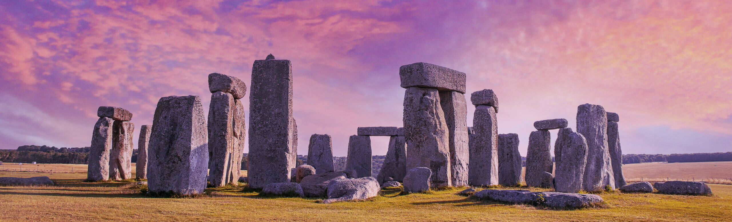 Stonehenge under dramatic sunset sky with long shadows